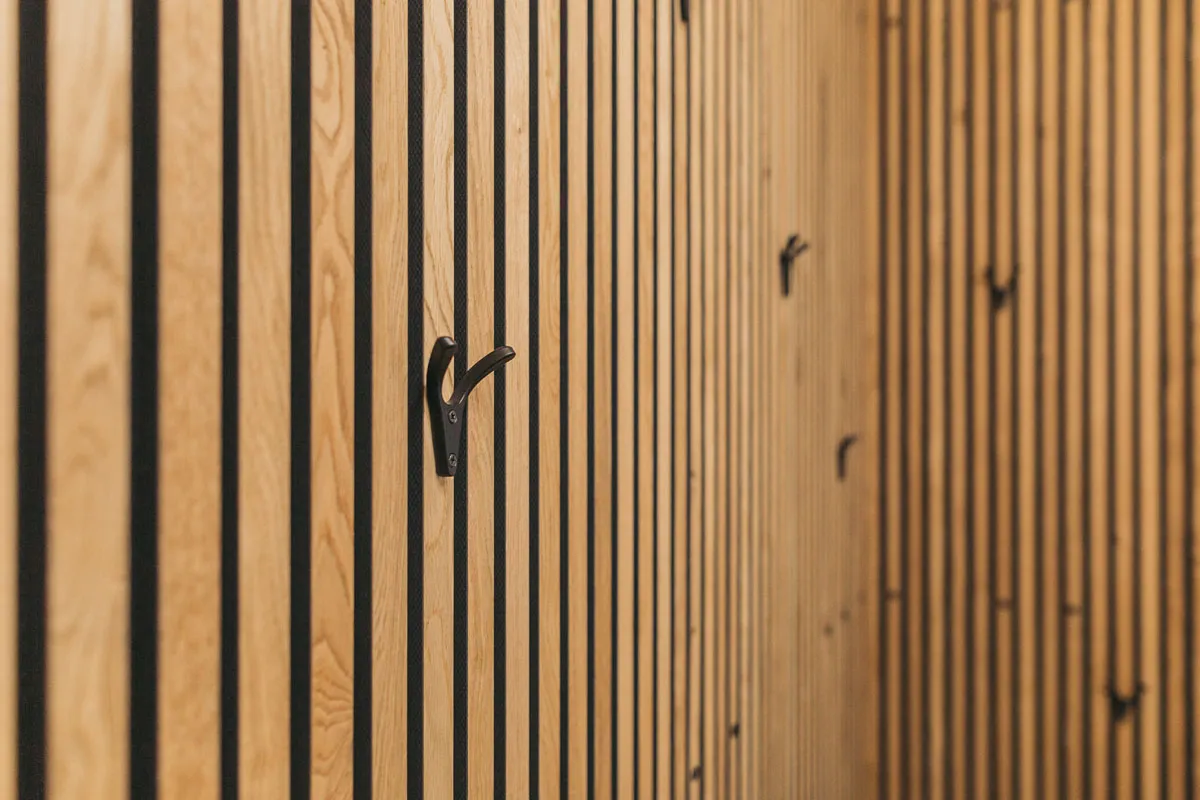 Cloakroom with wooden slat wall and black hooks